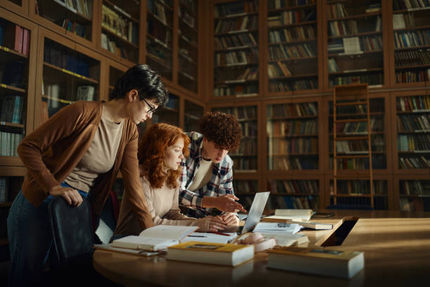 Group of high school students using laptop in library. stock photo