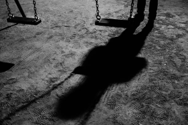 a swing and a suspicious figure at night - paedophilia imagens e fotografias de stock