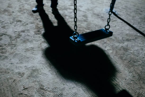 a swing and a suspicious figure at night - paedophilia imagens e fotografias de stock