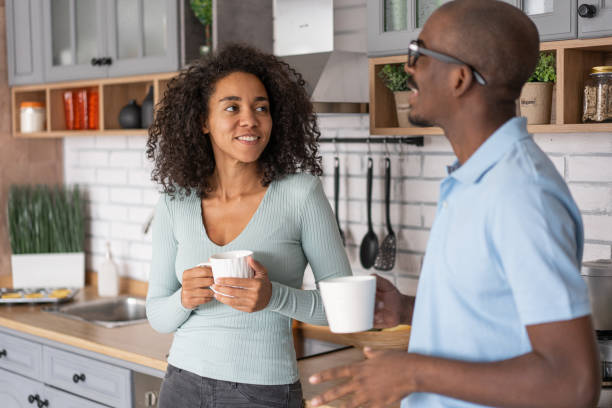 istock Affectionate black spouses, holding cups, drinking coffee and spending time in kitchen together, young loving african american man and woman having hot drinks and enjoying domestic weekend, free space 1458681177