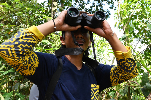 Young researcher observes birds in the rain forest of Aceh for research needs