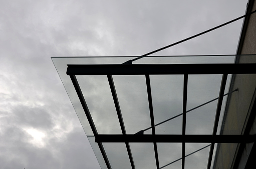 strut, suspended glass roof above the building entrance. bus station, railway station. cable wind braces. aluminum construction with windows above the pergola, screwed, anti sun, paneling, struts, strut