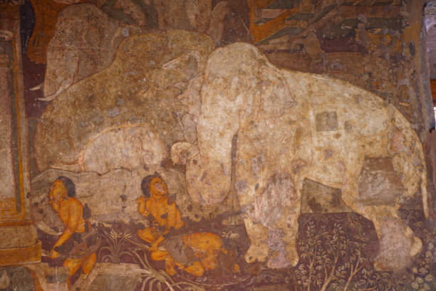 Ornate beautiful tempera painting of a white elephant with two other elephants in procession  with armed men depicted in a mural fresco on the walls of Ajanta Caves with radiant colours stock photo