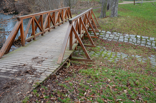 pedestrian bridge over a small gorge and a stream. it consists of two steel crossbeams. as the surface and railing of the bridge is made of brown painted planks. is long and narrow. polder wild, crossbeam, trampling