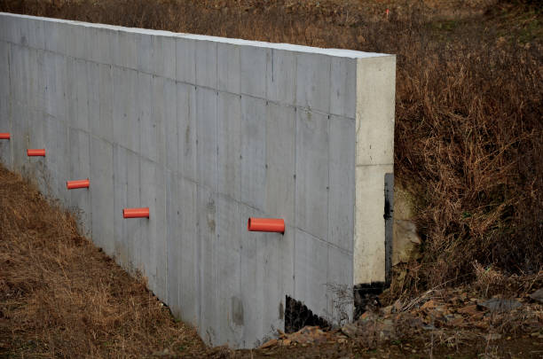 istock long straight supporting wall of cast cement mixer formwork. behind wall is soil that is brought out through the wall by drainage pipes. sewer pipe drain in line. construction site, white, field 1458689125