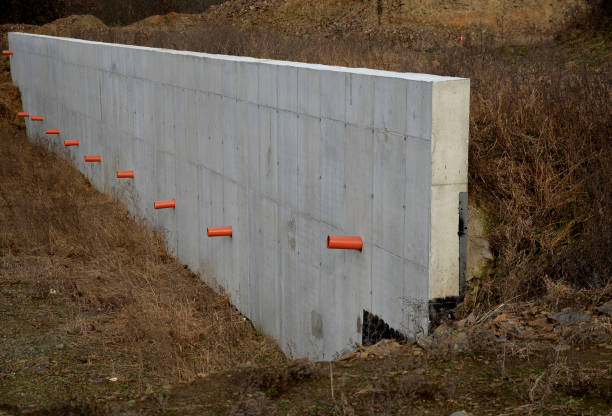 istock long straight supporting wall of cast cement mixer formwork. behind wall is soil that is brought out through the wall by drainage pipes. sewer pipe drain in line. construction site, white, field 1458689230