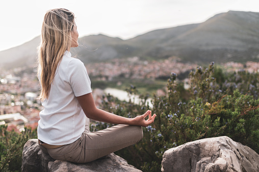 Young woman preforms yoga in mountains at sunset.