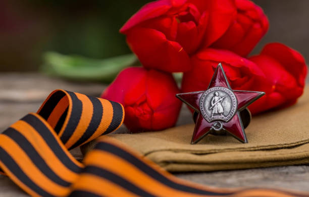 St. George's ribbon and the Order of the Red Star of the USSR World War II veteran on a wooden background. Translation into Russian: Workers of all countries unite. The concept of the May 9 holiday. St. George's ribbon and the Order of the Red Star of the USSR World War II veteran on a wooden background. Translation into Russian: Workers of all countries unite. The concept of the May 9 holiday. 1945 stock pictures, royalty-free photos & images