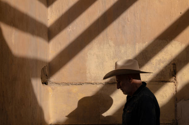 vista laterale dell'uomo adulto in cappello da cowboy contro il muro con la luce del sole e l'ombra - the western wall foto e immagini stock