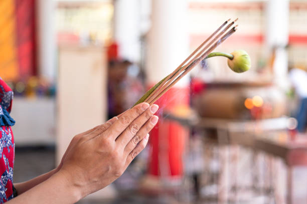 A human is paying homage at temple. Action of human hand is holding incense stick and lotus flower during pay homage at the temple in Chinese new year event. Close-up and selective focus. religious occupation stock pictures, royalty-free photos & images