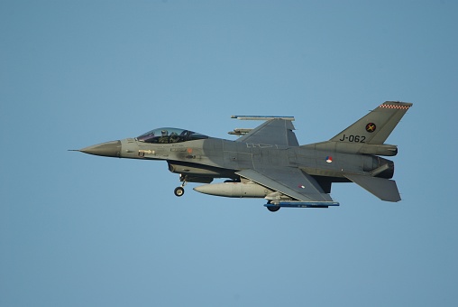 Military figher airplane landing on an airport runway.