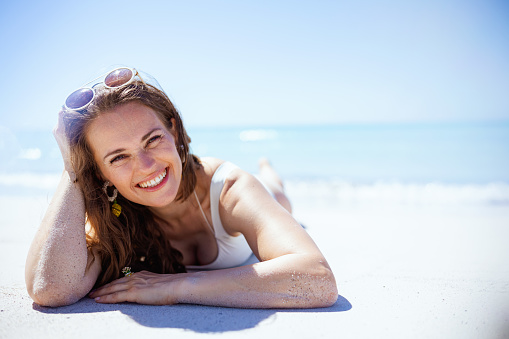 Portrait of happy elegant female laying at the beach.