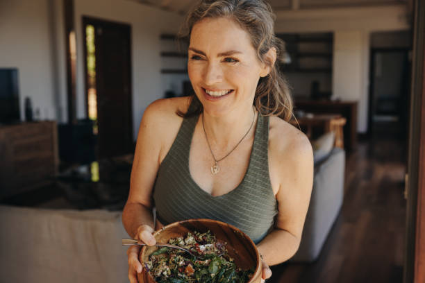 istock Fit senior woman smiling while holding a buddha bowl 1458706097