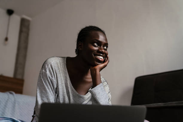 istock Young african american woman smiling while using laptop at home 1458708608
