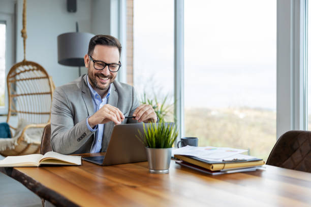 istock Smiling businessman working on laptop at home office 1458708712