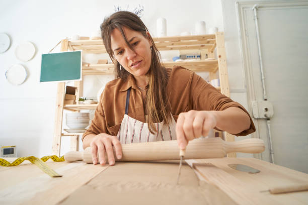 istock Woman in pottery workshop cutting clay while holding a rolling pin 1458708714