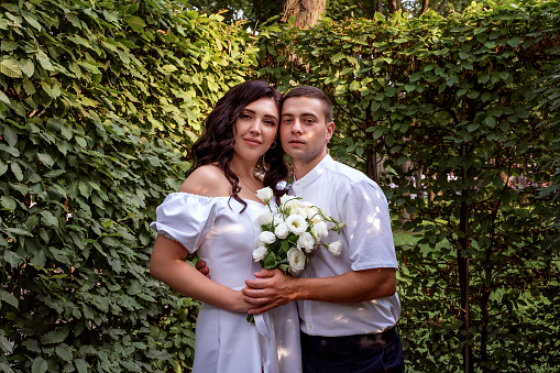 The guy snuggled up with love for his girlfriend in the bushes. Newlyweds in the park. Portrait of beautiful couple close-up. Summer kiss of the Ukrainian beauty.