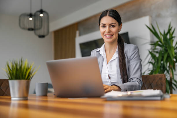 istock Female entrepreneur with laptop computer working at home office,looking at camera 1458709173