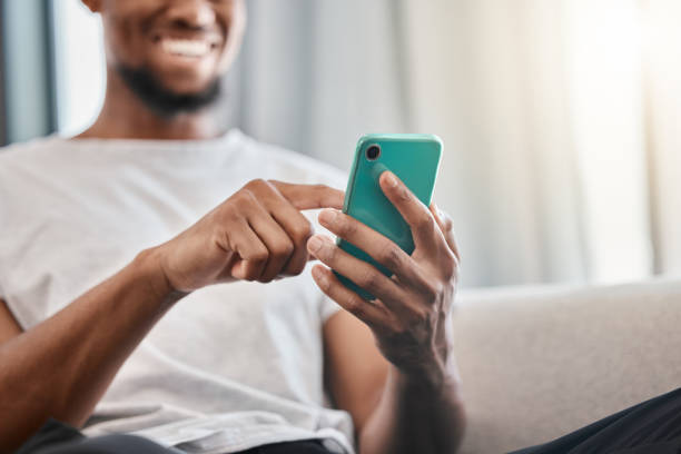 istock Hands, phone and social media with a black man typing a text message while sitting on a sofa in his home. Mobile, communication and networking with a male chatting from the living room in his house 1458718374