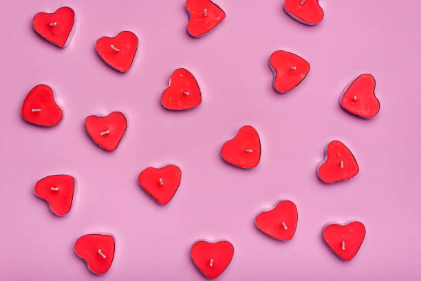 istock Group of heart-shaped scented candles extinguished on a pink background. 1458718501