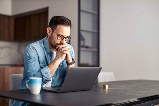 istock Frustrated unemployed man at home looking at laptop.Financial problems, recession and bankruptcy concept 1458718625