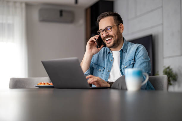 istock Smiling businessman working on laptop at home office 1458718631