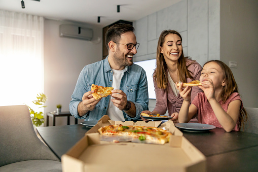 Happy family enjoying in weekend together.Happy family concept.They are eating pizza for lunch.