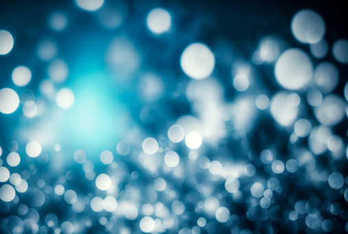 Abstract blue blurred bokeh background with various sized bright round shiny lights and dark spots
