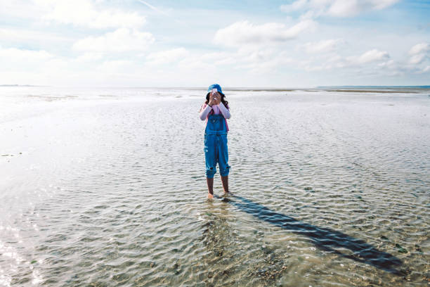 fille prenant une photo mobile et debout dans l’eau de mer à marée basse au crotoy, france - only teenage girls teenager adolescence sea photos et images de collection