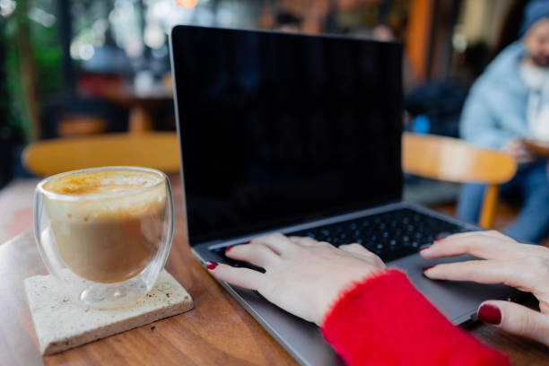 istock Young woman using laptop and drinking cofee in coffee shop 1458722585