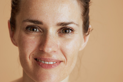 smiling modern woman with wet face washing isolated on beige.