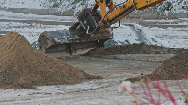 istock Industrial Excavator Scoop Distributing Sand on Street Surface During Winter Maintenance Roadworks 1458724859