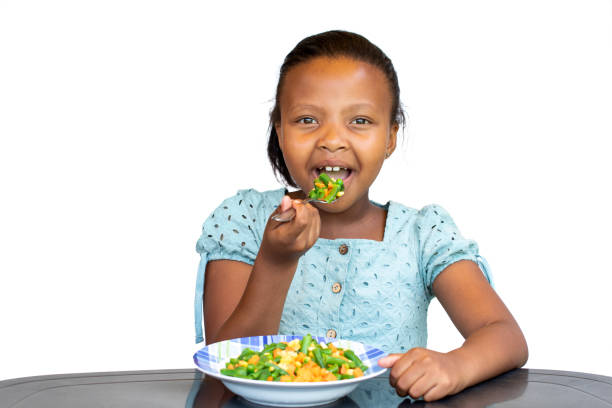 Cтоковое фото Маленькая африканская девочка ест здоровое блюдо за столом