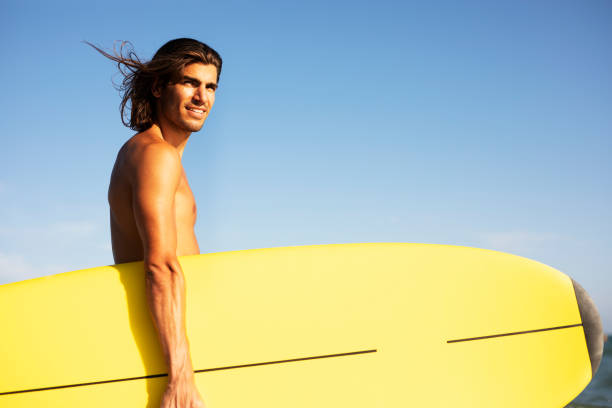 istock Young man with a surfboard on the beach. 1458725828