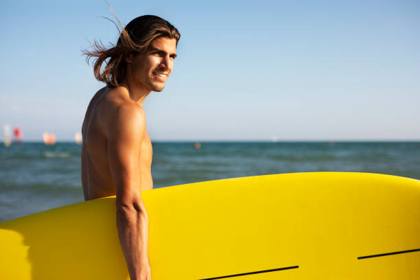 istock Young man with a surfboard on the beach. 1458725896