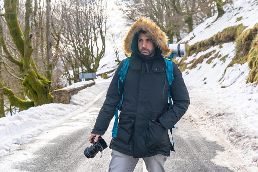Photographer man taking a photo in the snow, enjoying winter photography on a road