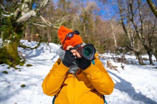 Photographer taking winter photos in the mountains with snow trekking with a backpack