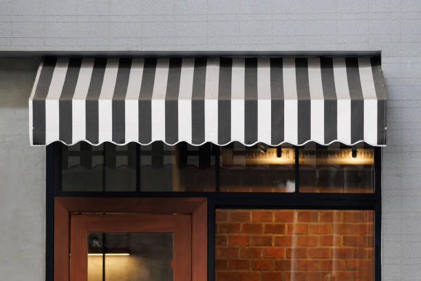 black and white striped awning over the front of store. blind canvas roof shading of the city shop. black and white striped awning over the front of store. blind canvas roof shading of the city shop. awning stock pictures, royalty-free photos & images