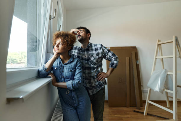 istock Thoughtful couple looking through window at their new apartment. 1458729079