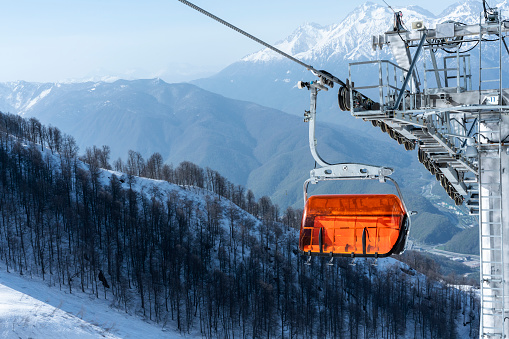 Empty bright orange ski chair lift in mountains in winter against the backdrop of snow Alpine skiing and snowboarding winter sports