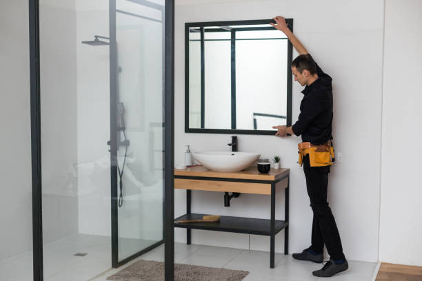istock The worker installs the mirror in the bathroom. 1458732117