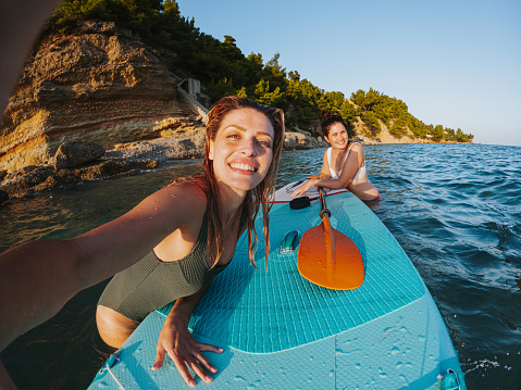 Selfie of two female friends on stand up paddle board