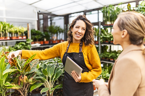 Woman at a garden center talking with an employee buying plants