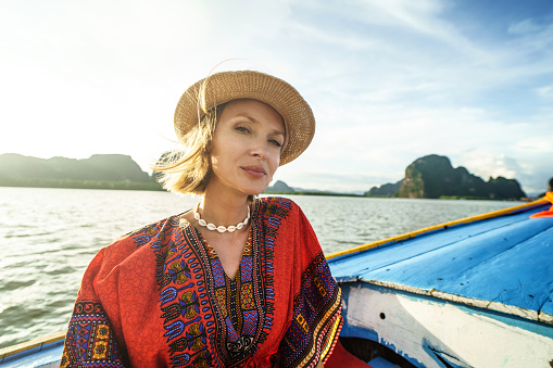 Travel tour by traditional long tail boat on tropical islands in Thailand. Woman relaxing, looking at the camera. Summer exotic holidays in Asia.
