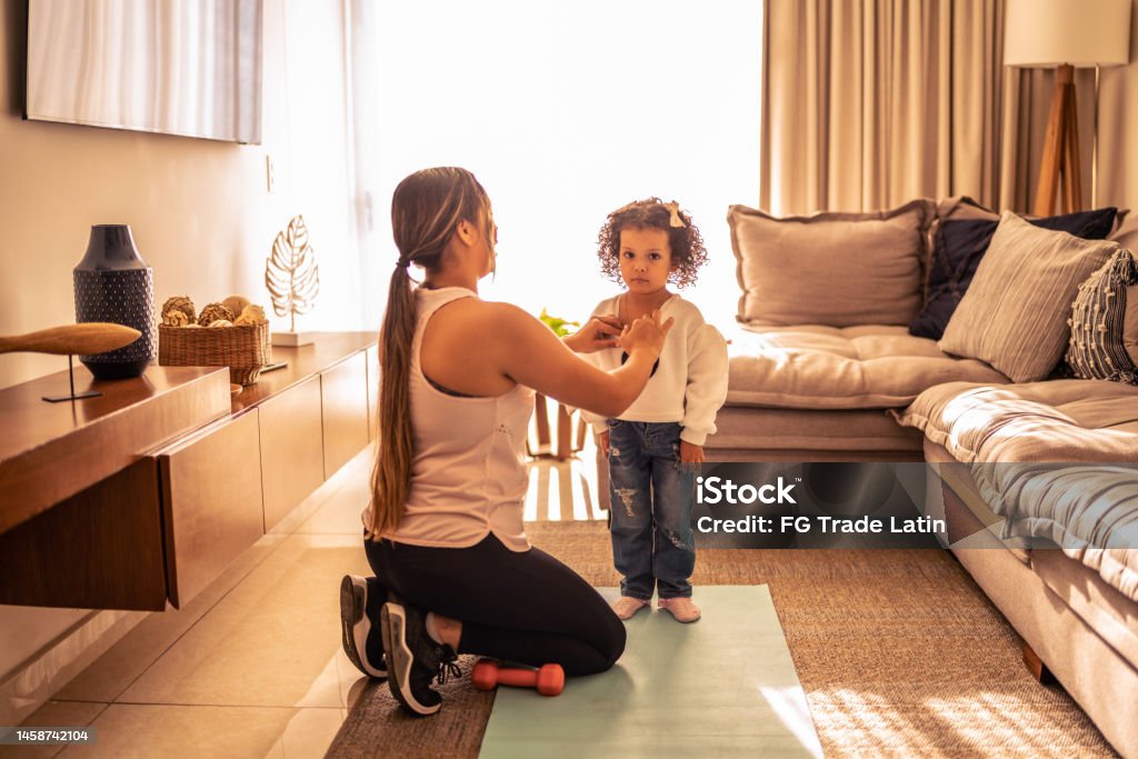 Mother helping daughter getting dressed at home A Helping Hand Stock Photo
