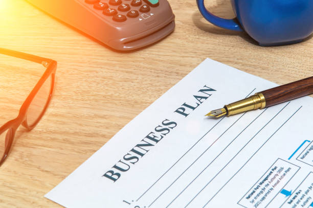 istock Business plan form on office desk with elegant pen and payment terminal. Business idea 1458742648