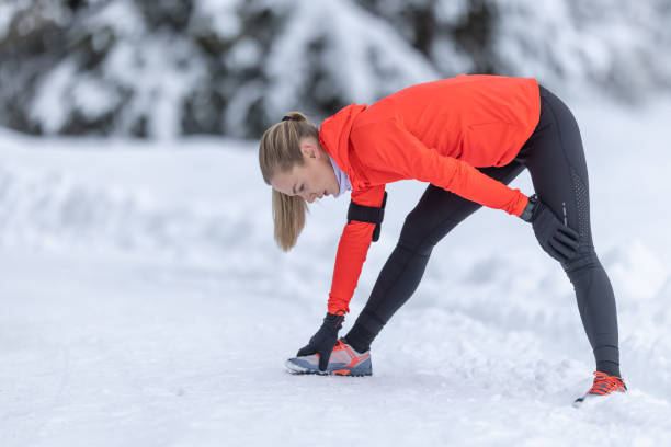 istock Athletic female runner doing stretching exercise, preparing for workout in the snowy winter park. 1458744983