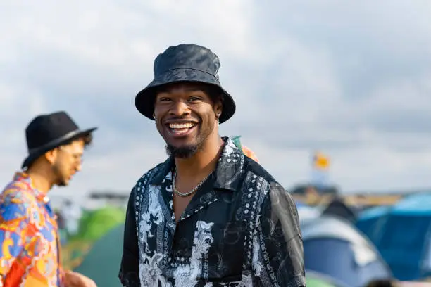 A young man at a festival in Lindisfarne, North East England. He is wearing a bucket hat while smiling and looking at camera.
