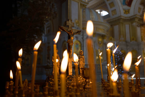 Cruz con crucifijo en foco. Concepto de religión cristiana. Cruz con crucifijo en foco, velas de cera encendidas, una iglesia ortodoxa, servicio conmemorativo, servicio funerario, oraciones por la salvación del alma. - foto de stock