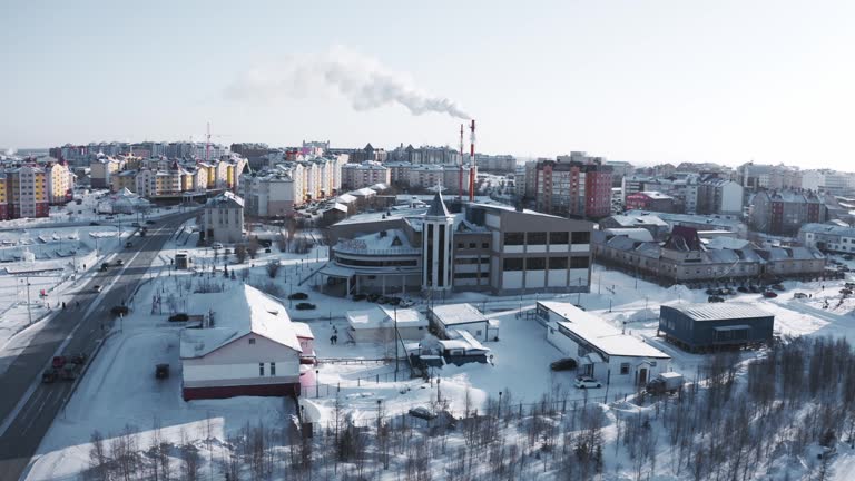 Siberian town in winter, view from the top. The copter is flying over buildings and trees. 4K